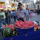 A street vendor selling watermelons talks on his mobile phone as he waits for customers at Taksim square in central Istanbul June 9, 2013. R A street vendor selling watermelons talks on his mobile phone as he waits for customers at Taksim square in central Istanbul June 9, 2013. R