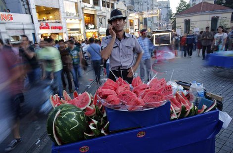 A street vendor selling watermelons talks on his mobile phone as he waits for customers at Taksim square in central Istanbul June 9, 2013. R A street vendor selling watermelons talks on his mobile phone as he waits for customers at Taksim square in central Istanbul June 9, 2013. R