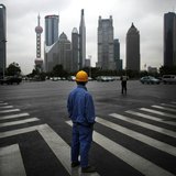A construction worker looks at Pudong financial district as he wait to cross an avenue in Shanghai May 30, 2013. REUTERS/Carlos Barria