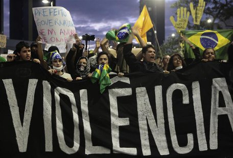 Demonstrators shout anti-government slogans behind a banner, which reads as 'violence', during one of many protests around Brazil's major ci Demonstrators shout anti-government slogans behind a banner, which reads as 'violence', during one of many protests around Brazil's major ci