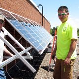 Technicians from Eland Electric install a solar panel array on the roof of Newman Catholic High School, June 18 2013