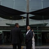 Presidential guards stand in front a black ribbon after a tribute for the victims of an explosion at the headquarters of the state oil monop