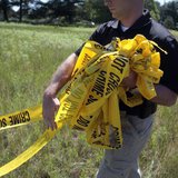 A federal investigator carries yellow crime tape at a field which investigators are prepared to dig up for the remains of former Teamsters b