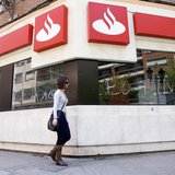 A woman walks past the vandalized windows of a Banco Santander branch in Valencia, May 14, 2013. The words on the windows read, "Botin" (a r