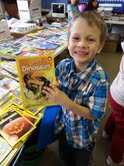 Noah Thurman, first grade, excited about a non-fiction dinosaur book