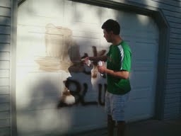 Man cleaning off a garage in southwest Fargo that was hit by vandals.
