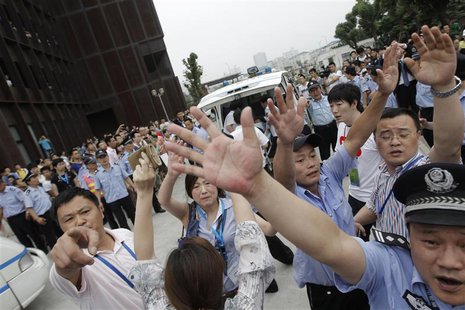 Policemen try to stop photographs from being taken after former England captain David Beckham left Tongji University surrounded by fans in S Policemen try to stop photographs from being taken after former England captain David Beckham left Tongji University surrounded by fans in S