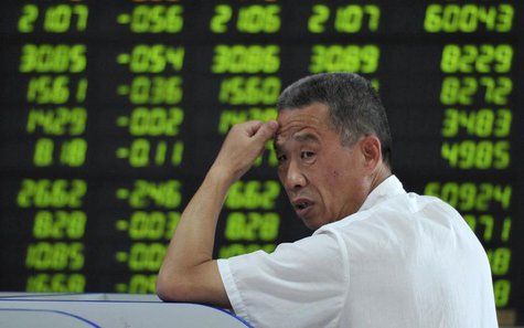 An investor looks back in front of an electronic board showing stock information filled with green-coloured figures, which indicate falling An investor looks back in front of an electronic board showing stock information filled with green-coloured figures, which indicate falling