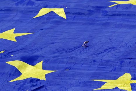 An organiser walks on a large European Union flag displayed in front of Romania's Parliament Building to mark EU Day in Bucharest May 9, 201 An organiser walks on a large European Union flag displayed in front of Romania's Parliament Building to mark EU Day in Bucharest May 9, 201