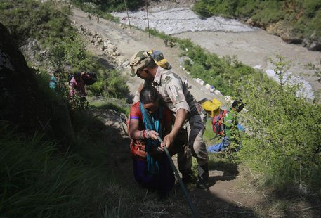 A woman is helped by a soldier to climb down a hill during a rescue operation at Govindghat in the Himalayan state of Uttarakhand June 21, 2