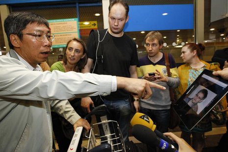 Journalists show an iPad with the picture of Edward Snowden, former contractor for the U.S. National Security Agency, to passengers of a fli Journalists show an iPad with the picture of Edward Snowden, former contractor for the U.S. National Security Agency, to passengers of a fli