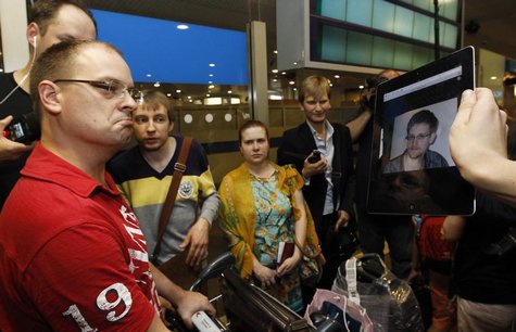 Journalists show an iPad with the picture of Edward Snowden, former contractor for the U.S. National Security Agency, to passengers of a fli Journalists show an iPad with the picture of Edward Snowden, former contractor for the U.S. National Security Agency, to passengers of a fli