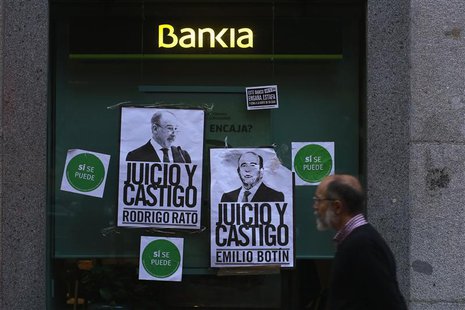 A man walks past a branch of Spain's lender bank Bankia with two posters depicting former Bankia CEO Rodrigo Rato (L ) and Emilio Botin, cha A man walks past a branch of Spain's lender bank Bankia with two posters depicting former Bankia CEO Rodrigo Rato (L ) and Emilio Botin, cha