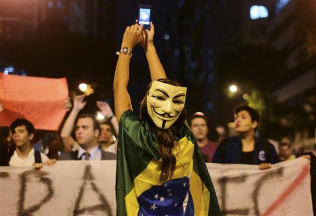 A demonstrator wearing a Guy Fawkes mask takes photos on her mobile phone during a protest in central Rio de Janeiro June 24, 2013. REUTERS/ A demonstrator wearing a Guy Fawkes mask takes photos on her mobile phone during a protest in central Rio de Janeiro June 24, 2013. REUTERS/