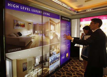 A sales representative (R) speaks to a visitor in front of photographs of a London upmarket property development for sale, inside a luxury h A sales representative (R) speaks to a visitor in front of photographs of a London upmarket property development for sale, inside a luxury h