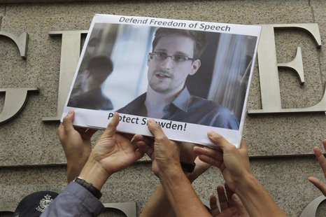 Protesters in support of Edward Snowden, a contractor at the National Security Agency (NSA), hold a photo of him during a demonstration outs Protesters in support of Edward Snowden, a contractor at the National Security Agency (NSA), hold a photo of him during a demonstration outs