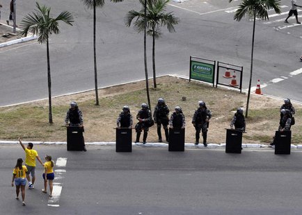 Soccer fans walk past members of a Brazilian special anti-riot unit at a security checkpoint outside the stadium before the Confederations C Soccer fans walk past members of a Brazilian special anti-riot unit at a security checkpoint outside the stadium before the Confederations C