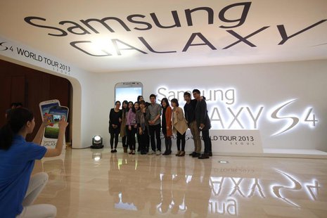 Visitors take a group photo next to a logo of Samsung Electronics Co Ltd's latest flagship smartphone S4 during its launch event at the comp Visitors take a group photo next to a logo of Samsung Electronics Co Ltd's latest flagship smartphone S4 during its launch event at the comp
