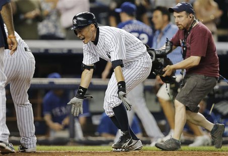 New York Yankees batter Ichiro Suzuki (C) spreads his arms as he runs past Texas Rangers relief pitcher Tanner Scheppers (3rd R, rear) to te New York Yankees batter Ichiro Suzuki (C) spreads his arms as he runs past Texas Rangers relief pitcher Tanner Scheppers (3rd R, rear) to te