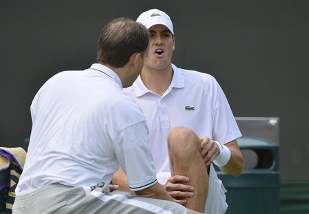 John Isner of the U.S. reacts as a trainer attends to his injured knee, before he retired from his men's singles tennis match against Adrian John Isner of the U.S. reacts as a trainer attends to his injured knee, before he retired from his men's singles tennis match against Adrian