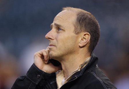 New York Yankees general manager Brian Cashman talks on his cellphone during batting practice prior to Game 4 of the MLB ALCS baseball playo New York Yankees general manager Brian Cashman talks on his cellphone during batting practice prior to Game 4 of the MLB ALCS baseball playo