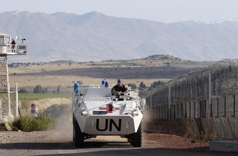 United Nations (U.N.) peacekeeping soldiers from Austria drive past an observation tower near the Quneitra border crossing between Israel an United Nations (U.N.) peacekeeping soldiers from Austria drive past an observation tower near the Quneitra border crossing between Israel an