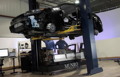 Team members raise a Chevrolet Volt electric vehicle on a hoist after releasing the battery from the underside at a design studio in Troy, M Team members raise a Chevrolet Volt electric vehicle on a hoist after releasing the battery from the underside at a design studio in Troy, M