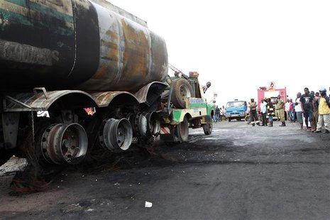 Uganda firefighters clean a road with water at the scene of a fatal road accident that led to a fuel tanker catching fire that killed and in Uganda firefighters clean a road with water at the scene of a fatal road accident that led to a fuel tanker catching fire that killed and in