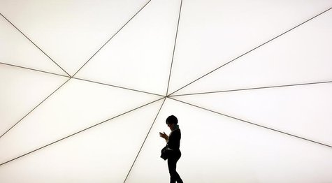 A woman looks her mobile phone as she walks past a Samsung stand at the Mobile World Congress in Barcelona February 25, 2013. REUTERS/Albert A woman looks her mobile phone as she walks past a Samsung stand at the Mobile World Congress in Barcelona February 25, 2013. REUTERS/Albert
