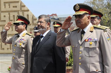 Egypt's President Mohamed Mursi (C) stands after laying a wreath during his visit to the tomb of former President Anwar al-Sadat and the Tom Egypt's President Mohamed Mursi (C) stands after laying a wreath during his visit to the tomb of former President Anwar al-Sadat and the Tom