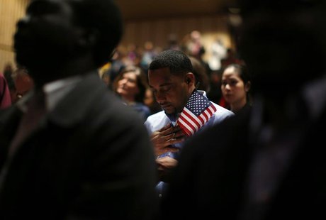 Immigrants stand for the invocation during a naturalization ceremony to become new U.S. citizens at Boston College in Chestnut Hill, Massach Immigrants stand for the invocation during a naturalization ceremony to become new U.S. citizens at Boston College in Chestnut Hill, Massach