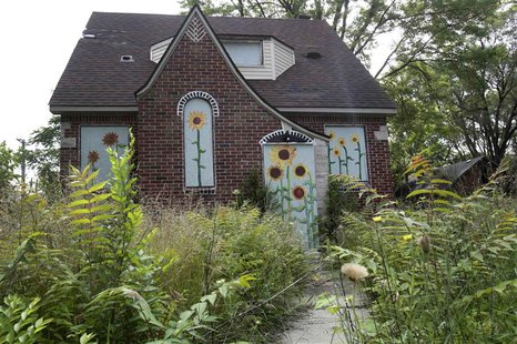 Overgrown grass and weeds are seen around a vacant house that has flowers painted on the boards to keep vandals out in the Brightmoor neighb Overgrown grass and weeds are seen around a vacant house that has flowers painted on the boards to keep vandals out in the Brightmoor neighb