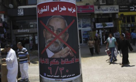 People walk past a defaced poster of Muslim Brotherhood leader Mohammed Badie with Arabic text which reads "Together to down brotherhood's p People walk past a defaced poster of Muslim Brotherhood leader Mohammed Badie with Arabic text which reads "Together to down brotherhood's p