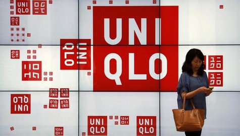A woman checks her phone in front of a panel outside the flagship store of Japanese fashion house Uniqlo at Hong Kong's Causeway Bay shoppin A woman checks her phone in front of a panel outside the flagship store of Japanese fashion house Uniqlo at Hong Kong's Causeway Bay shoppin