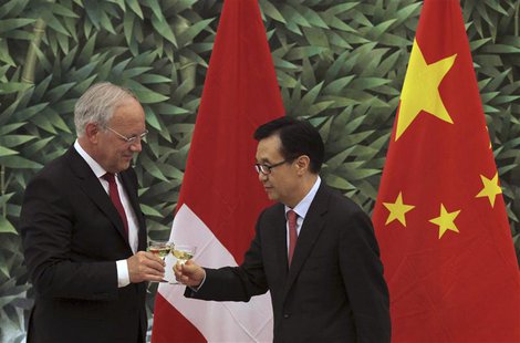 Chinese Commerce Minister Gao Hucheng (R) toasts with Swiss Economy Minister Johann Schneider-Ammann in front of the national flags of Switz Chinese Commerce Minister Gao Hucheng (R) toasts with Swiss Economy Minister Johann Schneider-Ammann in front of the national flags of Switz