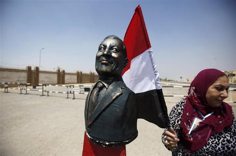 A supporter of Egypt's former President Hosni Mubarak holding an Egyptian flag stands next to a bust of Mubarak outside a police academy whe A supporter of Egypt's former President Hosni Mubarak holding an Egyptian flag stands next to a bust of Mubarak outside a police academy whe