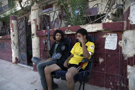 A Free Syrian Army fighter wearing a wig (L), carries his weapon as he sits next to his fellow fighter in Deir al-Zor, July 5, 2013. REUTERS A Free Syrian Army fighter wearing a wig (L), carries his weapon as he sits next to his fellow fighter in Deir al-Zor, July 5, 2013. REUTERS