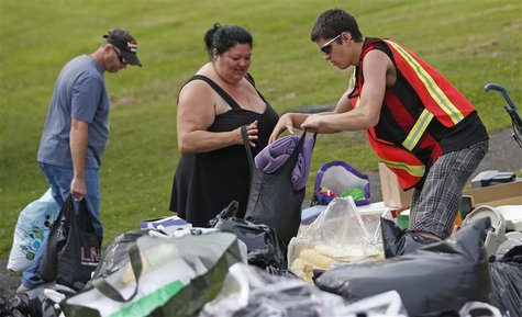 A volunteer gives clothes to a woman who's been evacuated from her home at the Polyvalente Montignac, the school sheltering the people who w A volunteer gives clothes to a woman who's been evacuated from her home at the Polyvalente Montignac, the school sheltering the people who w