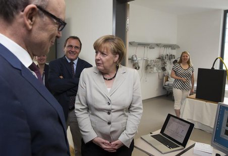German Chancellor Angela Merkel (3rdL) listens to a presentation of a magnetic tracking system at the newly opened Life Science Campus at Gr German Chancellor Angela Merkel (3rdL) listens to a presentation of a magnetic tracking system at the newly opened Life Science Campus at Gr