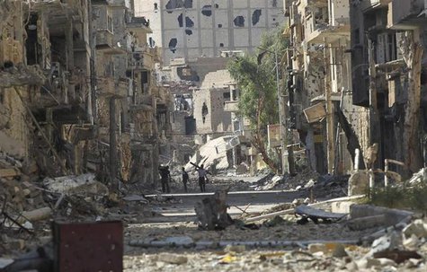 Residents carry their belongings as they walk along a damaged street filled with debris in Deir al-Zor July 7, 2013. Picture taken July 7, 2 Residents carry their belongings as they walk along a damaged street filled with debris in Deir al-Zor July 7, 2013. Picture taken July 7, 2