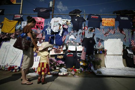 People look at mementos at a memorial dedicated to the 19 firefighters killed in the nearby wildfire in Prescott, Arizona, July 8, 2013. REU People look at mementos at a memorial dedicated to the 19 firefighters killed in the nearby wildfire in Prescott, Arizona, July 8, 2013. REU