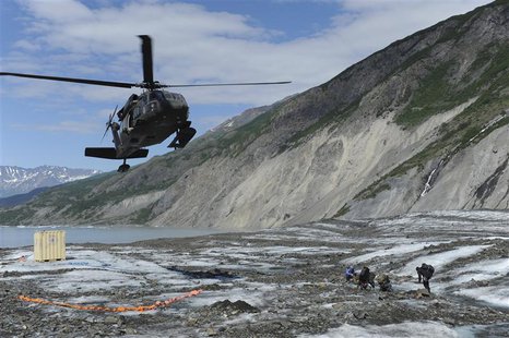 Members of a specialized investigative team from the Joint POW/MIA Accounting Command wait as a UH-60 Blackhawk helicopter comes in for a la Members of a specialized investigative team from the Joint POW/MIA Accounting Command wait as a UH-60 Blackhawk helicopter comes in for a la