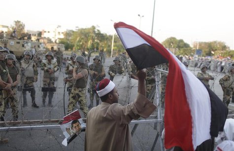 A supporter of ousted Egyptian President Mohamed Mursi waves an Egyptian flag in front of security personnel outside of the Republican Guard A supporter of ousted Egyptian President Mohamed Mursi waves an Egyptian flag in front of security personnel outside of the Republican Guard