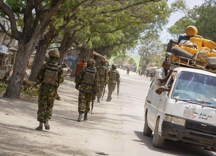 Soldiers, who are serving with the Kenyan Contingent of the African Union Mission in Somalia (AMISOM), patrol along a street as a commuter t Soldiers, who are serving with the Kenyan Contingent of the African Union Mission in Somalia (AMISOM), patrol along a street as a commuter t