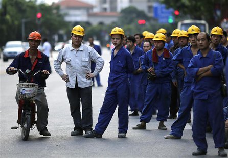 Construction workers wait for a bus after their workday at Pudong financial district in Shanghai July 8, 2013. China's resolve to revamp its Construction workers wait for a bus after their workday at Pudong financial district in Shanghai July 8, 2013. China's resolve to revamp its