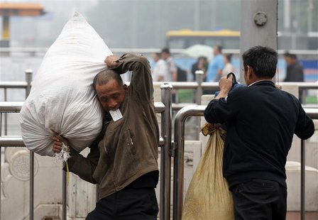 A migrant worker holding a ticket in his mouth carries his luggage at Beijing railway station June 7, 2013. REUTERS/Kim Kyung-Hoon A migrant worker holding a ticket in his mouth carries his luggage at Beijing railway station June 7, 2013. REUTERS/Kim Kyung-Hoon