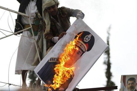 A pro-democracy protester burn an image of Lieutenant- General Abdel Fattah El Sisi, Egypt's Commanding General and Minister of Defense and A pro-democracy protester burn an image of Lieutenant- General Abdel Fattah El Sisi, Egypt's Commanding General and Minister of Defense and