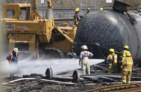 Firefighters spray wagons at the site of the train wreck in Lac-Megantic July 14, 2013. REUTERS/Mathieu Belanger Firefighters spray wagons at the site of the train wreck in Lac-Megantic July 14, 2013. REUTERS/Mathieu Belanger