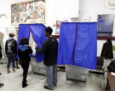 A poll worker assists a voter with the voting booth curtain before voting during the U.S. presidential election at the Penrose recreation ce A poll worker assists a voter with the voting booth curtain before voting during the U.S. presidential election at the Penrose recreation ce