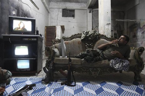 A Free Syrian Army fighter rests on a sofa as he watches television and surveillance monitors inside a room in Aleppo's Karm al-Jabal distri A Free Syrian Army fighter rests on a sofa as he watches television and surveillance monitors inside a room in Aleppo's Karm al-Jabal distri